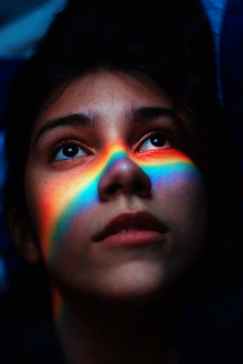 woman with rainbow light reflecting her face
